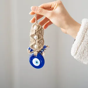 Detail of handmade evil eye hanging ornament with blue glass, pearls and jute rope