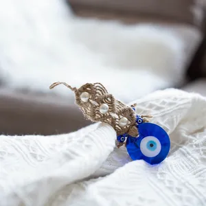 Close-up of glass Evil Eye wall hanging with woven rope and white pearl accents