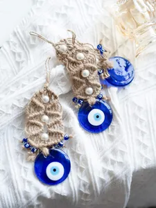 Detail of handmade evil eye charm with blue glass, woven rope and pearl accents