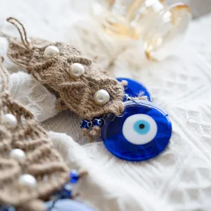 Detail of macrame evil eye wall hanging with jute rope, white pearls and blue glass