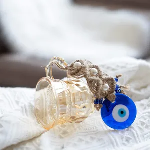 Detail of amber glass cup with Turkish blue evil eye pendant and rope pearl accents