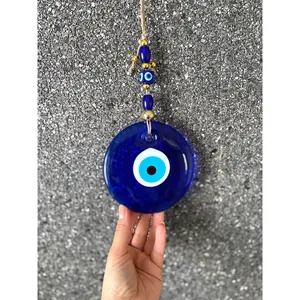 Turkish Evil Eye wall hanging ornament with large blue glass disk on a stone wall