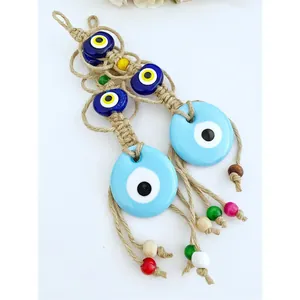 Dettaglio di decorazione murale Evil Eye in macramè con perle in vetro e nappe in legno