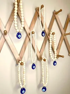 Detail of Nordic evil eye charms with natural wooden beads hanging on a wooden rack