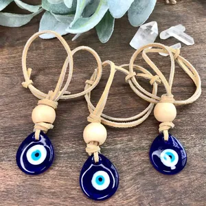 Three evil eye pendants with wooden beads and leather cords on dark wood background