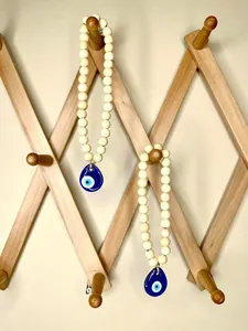 Close-up of wooden bead hanging decor with a blue glass evil eye teardrop pendant