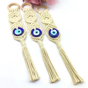 Detailed view of three handmade bohemian wall hangings with evil eye beads and cotton tassels