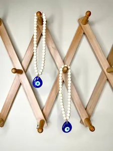Detail of blue evil eye pendants with white beads hanging on a wooden wall rack