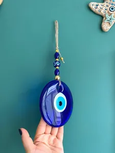 Detail of Turkish blue evil eye wall hanging with glass nazar bead and braided rope