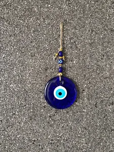 Detailed close-up of large blue evil eye wall hanging with jute rope and beads