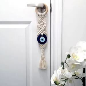 Handmade Bohemian evil eye wall hanging with woven cotton rope and tassels on a wooden ring