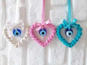 Detailed macro view of handmade woven heart charms with evil eye beads and ribbons