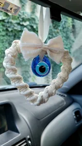 Detailed macro view of handmade boho evil eye car charm with lace bow and woven heart