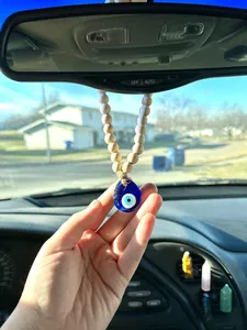 Detail of Boho wood bead Evil Eye car charm hanging from a rearview mirror