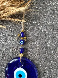 Macro detail of Turkish blue glass Evil Eye charm with jute rope and metallic beads