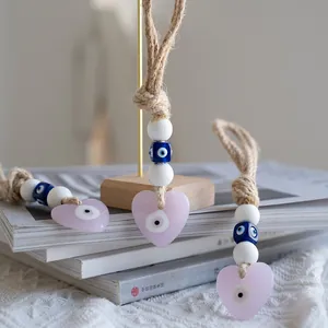 Close-up of pink heart Evil Eye wall charms with woven rope and blue bead details