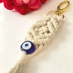 Close-up of macrame keychain with woven cotton fringes and blue evil eye bead detail