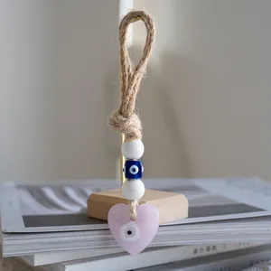 Detail of handmade evil eye heart ornament with jute rope and beads on a wooden stand