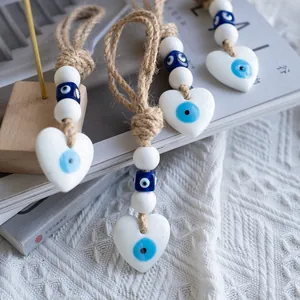 Detail of heart evil eye wall decor with jute rope and blue beads on soft fabric