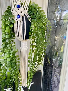 Detail of macrame plant hanger with handmade woven cotton rope and blue evil eye beads