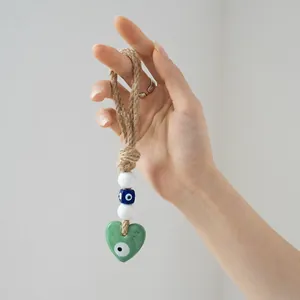 Detailed view of handmade Evil Eye wall hanging with heart pendant and jute rope
