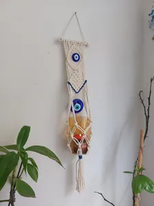 Detailed macro view of macrame wall hanging with evil eye beads holding amber candle glass