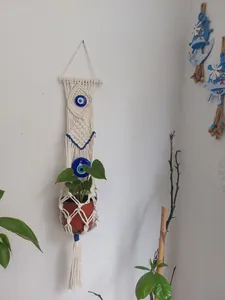 Detail of bohemian hand-woven macrame plant hanger with blue evil eye beads and tassels