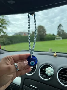 Close-up of handmade woven blue evil eye car hanging ornament on rearview mirror