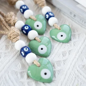 Detailed view of handmade green heart Evil Eye wall charms with woven jute rope