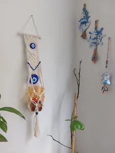 Detail of bohemian hand-woven cotton macrame wall hanging with blue evil eye beads