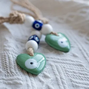Macro shot of green heart-shaped evil eye wall hanging decor with jute rope and beads