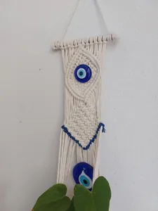 Detail of handmade macrame wall hanging featuring blue evil eye glass charms
