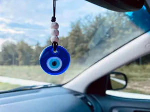 Detail of hand-woven car ornament featuring blue glass evil eye and stone beads