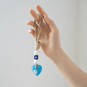 Macro shot of blue heart glass evil eye wall decor with braided rope and white beads