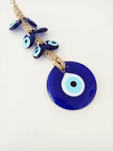 Detail of handmade evil eye charm with jute rope and blue glass beads on white background