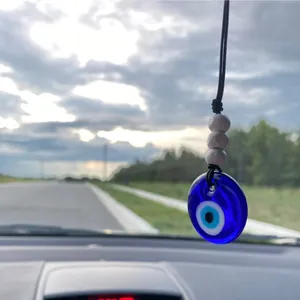 Handmade Evil Eye car charm with blue beads hanging on a vehicle rearview mirror
