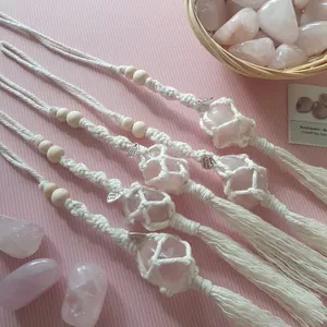Detail of four handmade pink salt stone pendants with woven cotton rope and tassels