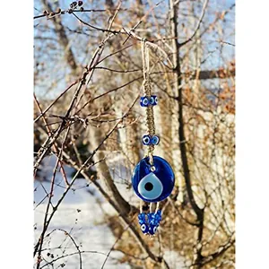 Turkish evil eye wall hanging with blue glass beads and tassels on a snowy branch