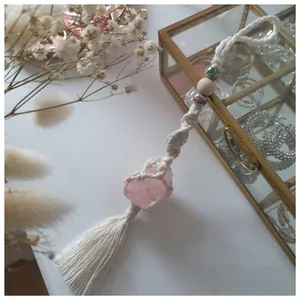 Macro detail of macrame wall hanging with pink salt stone and heart charm pendant