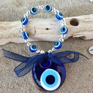 Ciondolo malocchio turco in vetro blu con bracciale di perline su sfondo sabbia