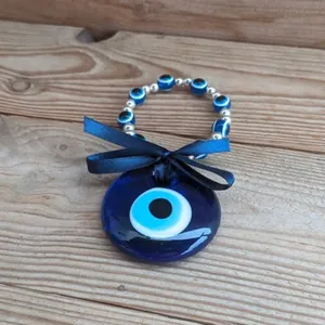 Ciondolo malocchio turco in vetro blu con perline e nastro su fondo in legno