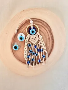 Detail of macrame evil eye car charm with white cotton rope and blue eye beads