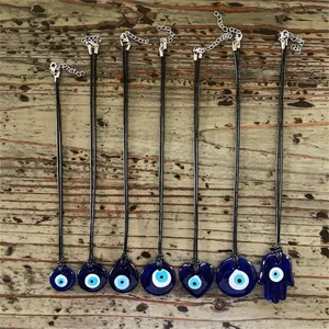 Variété de pendentifs Oeil Mauvais et Main de Hamsa en verre sur fond en bois vintage