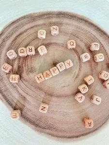 Close-up of wooden letter beads spelling HAPPY on a natural wood slice background