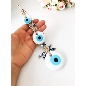 Detail of hand-woven Evil Eye wall hanging with three blue glass charms for home decor