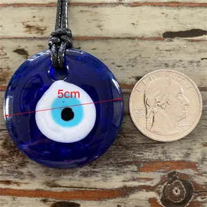 Détail d'un pendentif Evil Eye bleu de 5cm avec référence de taille sur fond en bois