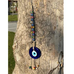 Dettaglio del decoro murale Evil Eye fatto a mano con perline colorate su un ramo naturale