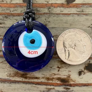 Détail du pendentif Œil maléfique en verre bleu de 4 cm sur un fond en bois naturel