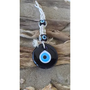 Detailed macro view of handmade boho evil eye glass pendant with woven tassel cord