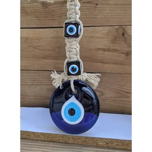 Close-up of bohemian handmade macrame evil eye wall hanging with blue glass pendant